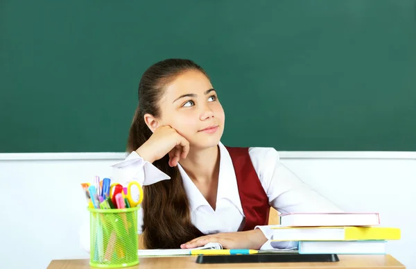 Beautiful little schoolgirl in classroom near blackboard — Stock Photo, Image
