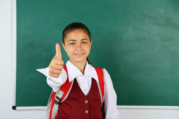 Belle petite fille debout près du tableau noir dans la salle de classe — Photo