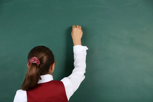 Vacker liten flicka skriver på tavlan i klassrummet — Stockfoto