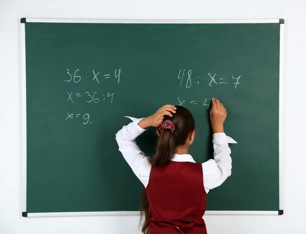 Beautiful little girl writes on blackboard in classroom — Stock Photo, Image