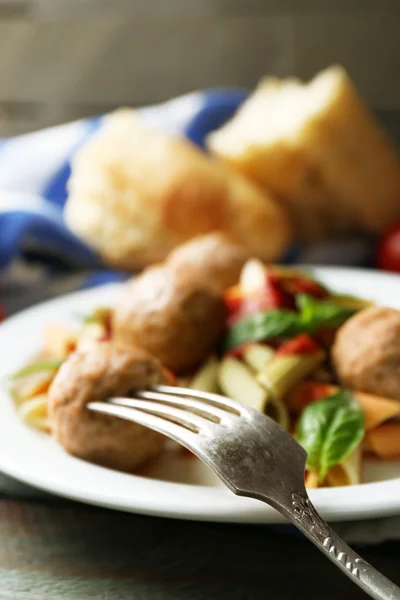 Pasta con albóndigas en plato, sobre fondo de mesa de madera —  Fotos de Stock