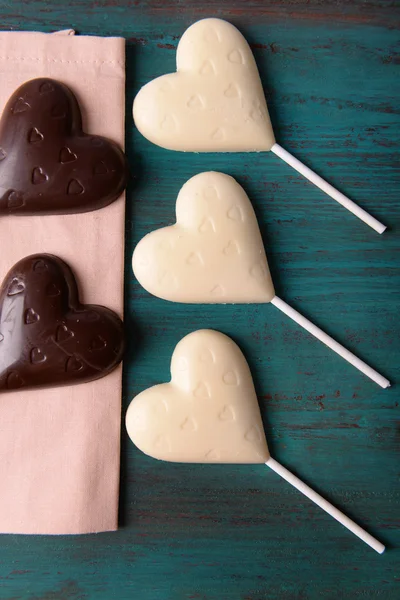 Chokolade hjerteformede slik på pinde på træ baggrund - Stock-foto