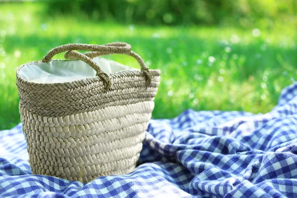 Cesto di vimini e plaid per picnic su erba verde — Foto Stock