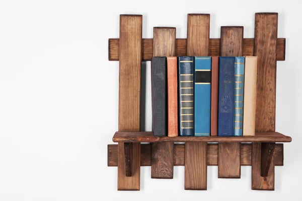 Wooden shelf with books on wall — Stock Photo, Image