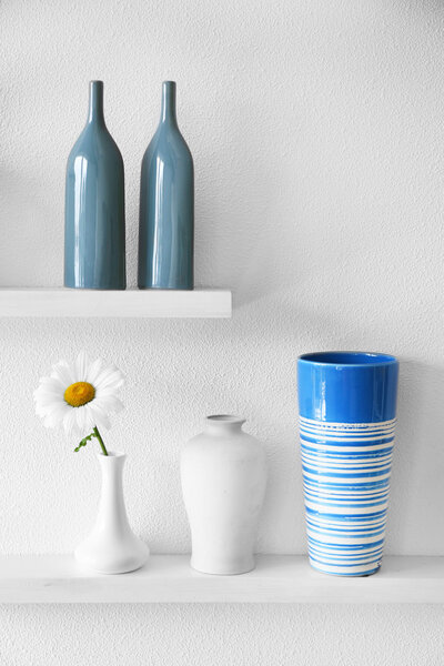 Decorative vases on wooden shelf