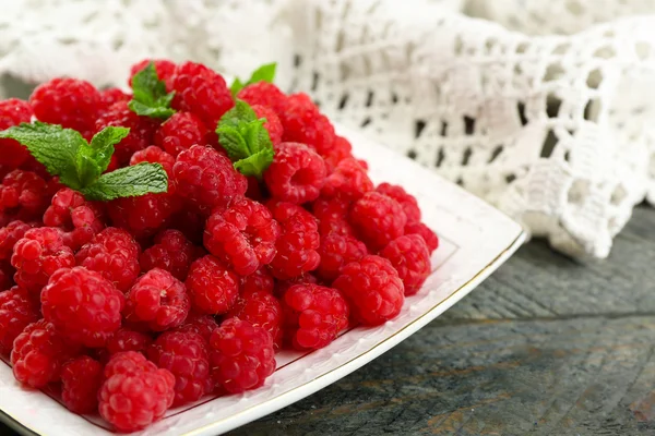 Sweet raspberries on plate on wooden  background — Stock Photo, Image