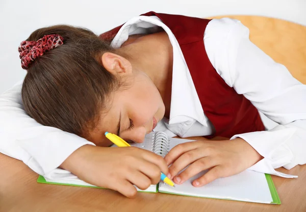 Beautiful little schoolgirl sleeping on desk Stock Photo