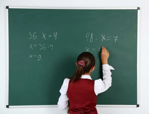 Menina bonita escreve no quadro negro em sala de aula — Fotografia de Stock