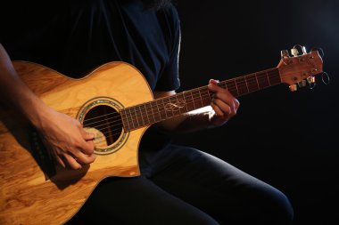 Genç adam akustik gitarla çalıyor.