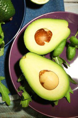 ahşap arka plan üzerine dilimlenmiş avokado, roka ve limon kireç