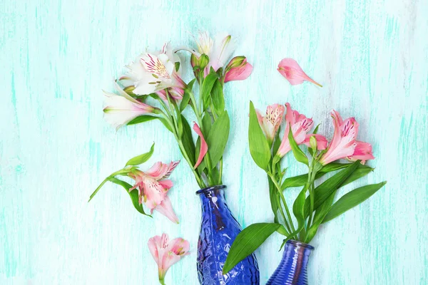 Beautiful alstroemeria in vases on wooden background — Stock Photo, Image