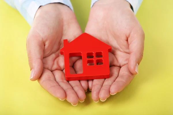 Female hands holding house on color background — Stock Photo, Image