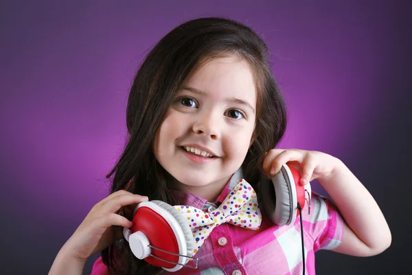 Menina bonita com fones de ouvido no fundo de cor — Fotografia de Stock