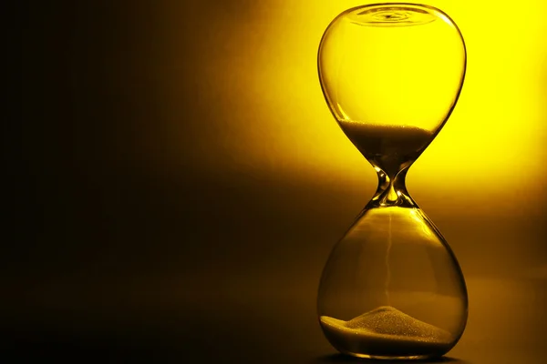 Reloj de arena sobre fondo amarillo oscuro — Foto de Stock