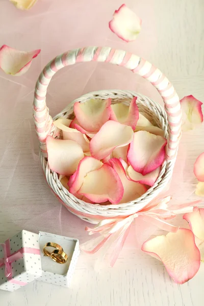 Cesta de casamento com pétalas de rosas na mesa, no fundo claro — Fotografia de Stock