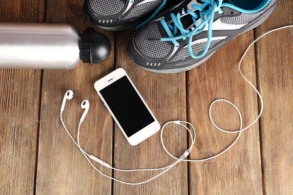 Zapatillas y auriculares en mesa de madera — Foto de Stock