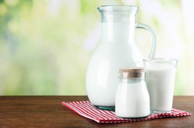 Sürahi, kavanoz ve süt doğa arka plan üzerinde ahşap tablo