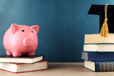 Kitap ve yazı tahtası arka plan üzerinde Grad şapka ile Piggy banka