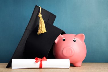 Grad şapka ve diploma tahta arka plan ile Piggy banka