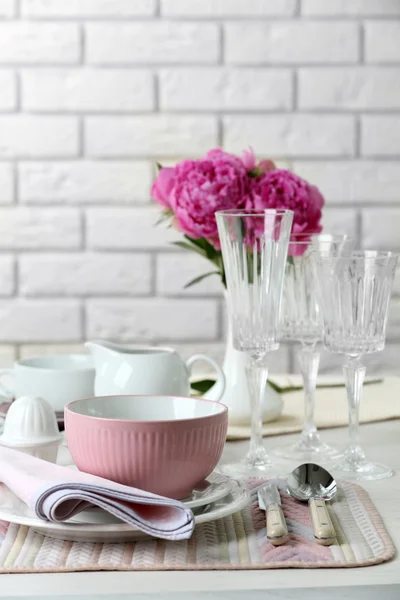 Cenário de mesa bonita com flores em vaso no fundo da parede de tijolo — Fotografia de Stock