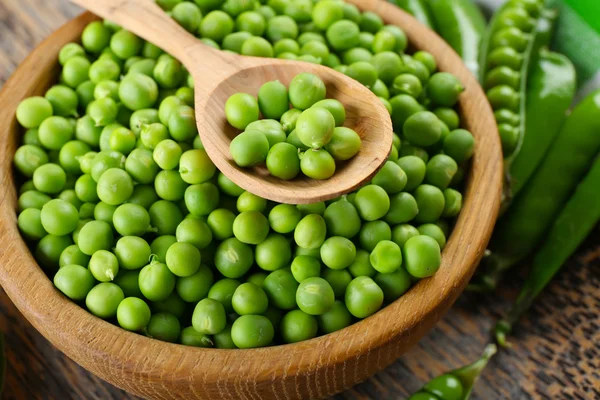 Guisantes verdes frescos en tazón en bandeja de madera, primer plano —  Fotos de Stock