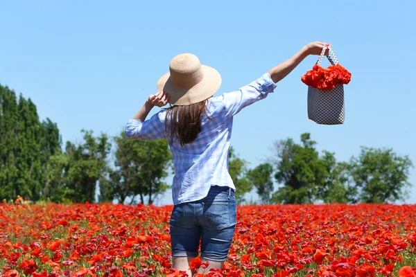 Mulher andando com saco no campo de papoula sobre fundo céu azul — Fotografia de Stock