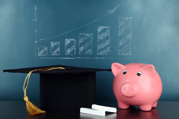 Piggy bank met grad hoed op blackboard achtergrond — Stockfoto