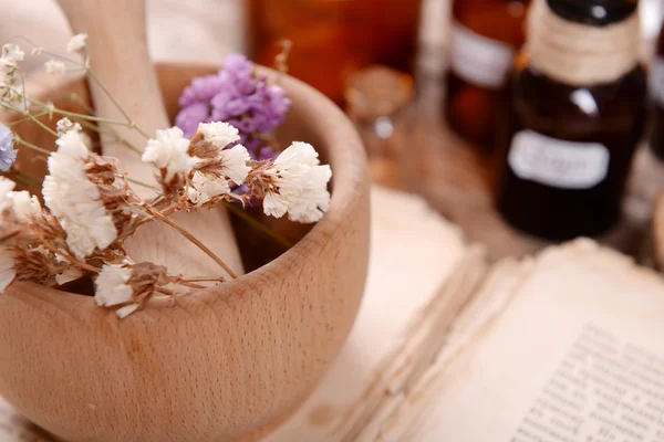 Livro velho com flores secas em argamassa e garrafas na mesa de perto — Fotografia de Stock