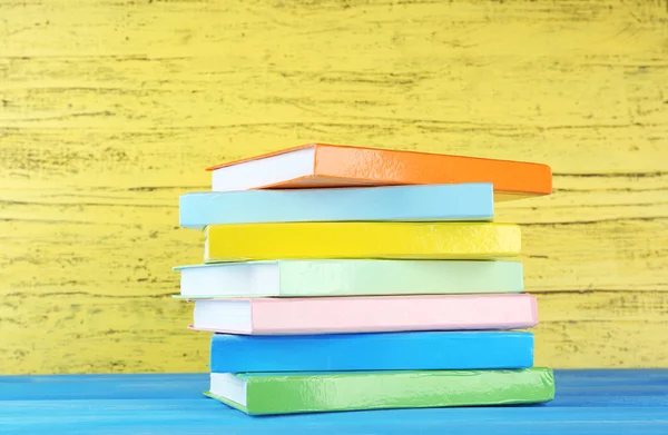 Livros coloridos sobre fundo de madeira amarelo — Fotografia de Stock
