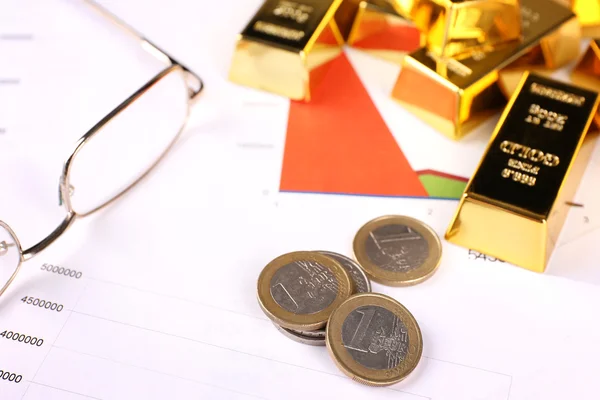 Gold bullion with coins on documents background