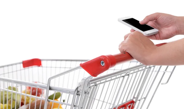 Young woman holding mobile phone and shopping cart isolated on white — Stock Photo, Image