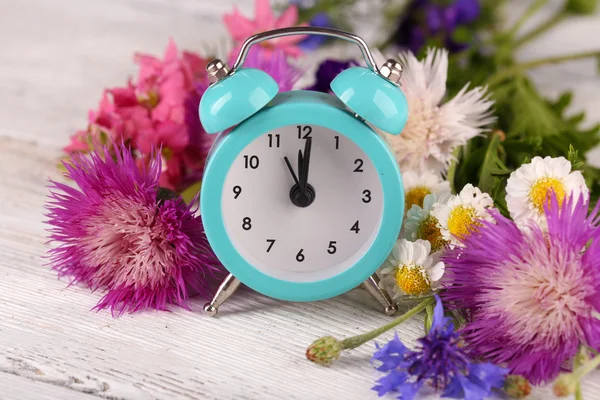 Alarm clock with wild flowers — Stock Photo, Image