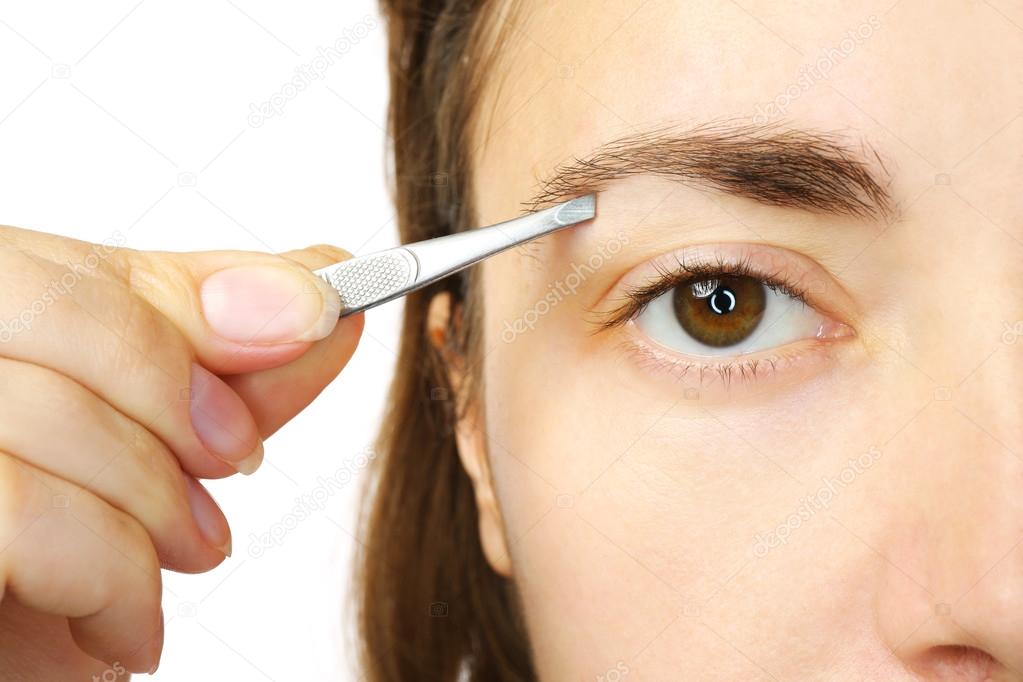 woman plucking eyebrows with tweezers