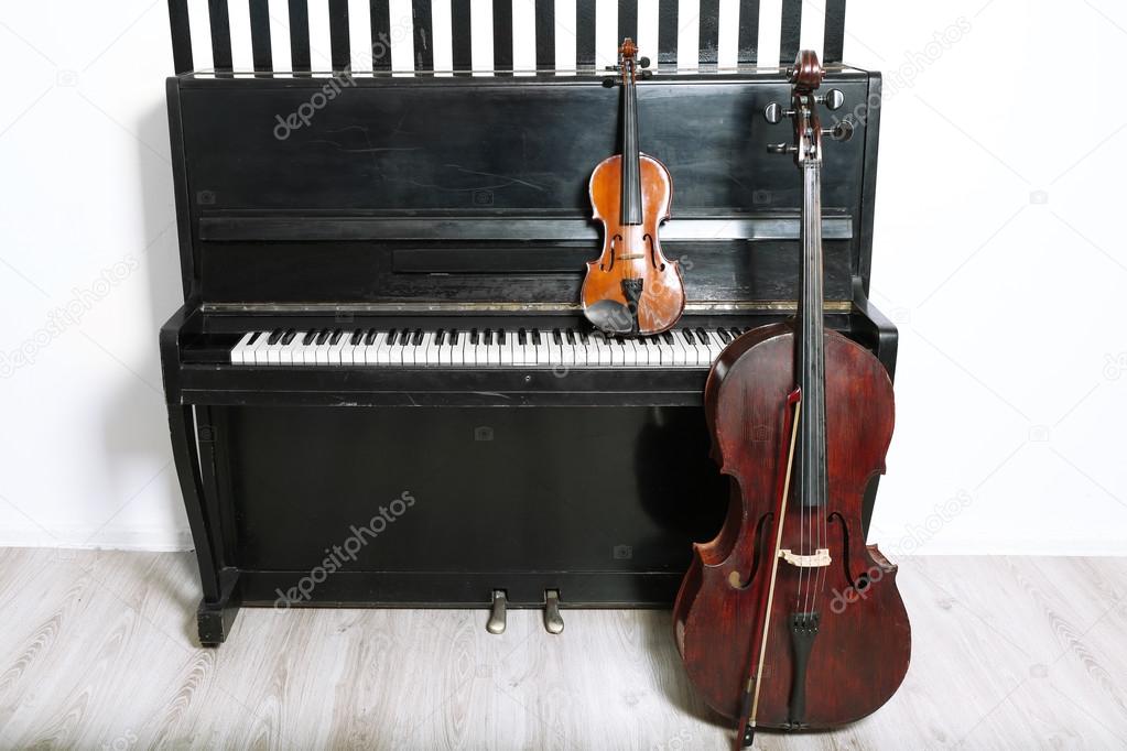 Piano, cello and violin on white wall background