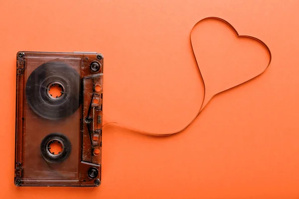 Cassette de audio con cinta magnética en forma de corazón sobre fondo naranja — Foto de Stock