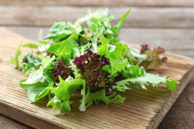 Ahşap kesim tahtasında karışık yeşil salata, yakın plan.