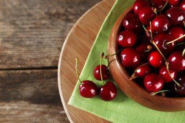 Kesme tahtası ahşap arka plan üzerinde peçeteye kase taze kiraz