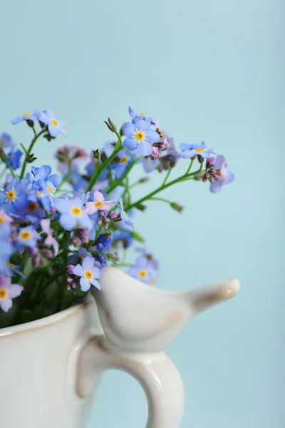 Forget-me-nots bloemen in cup, op blauwe achtergrond — Stockfoto