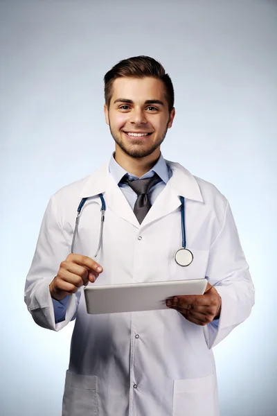 Médico masculino com comprimido sobre fundo azul — Fotografia de Stock