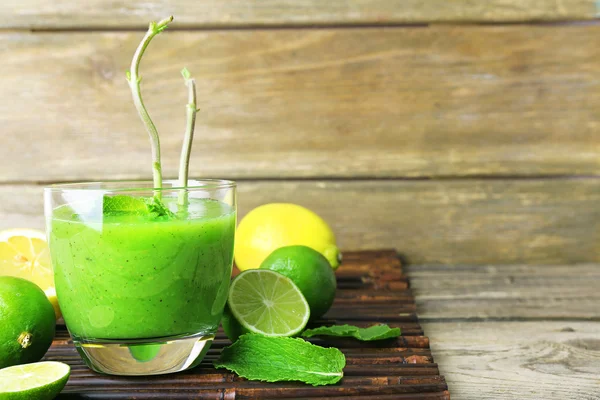 Copo de suco saudável verde com hortelã e frutas em fundo de madeira — Fotografia de Stock