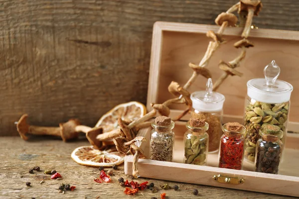 Assortment of spices in glass bottles on wooden background — Stock Photo, Image