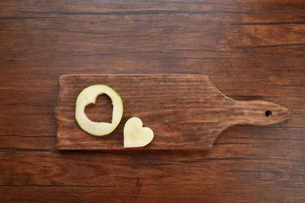 Apple slice with cut in shape of heart on wooden background — Stock Photo, Image