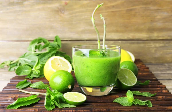 Bicchiere di succo sano verde con menta e frutta su sfondo di legno — Foto Stock