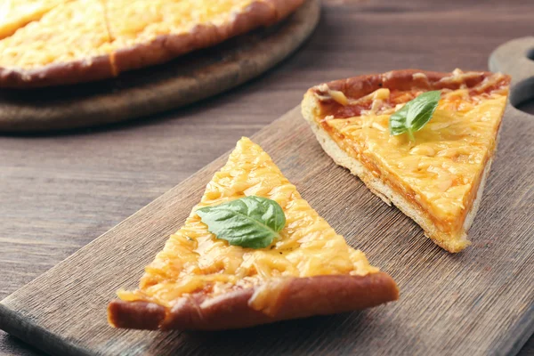 Fatias de pizza de queijo saboroso com manjericão na mesa de perto — Fotografia de Stock