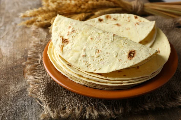 Montón de tortilla casera de harina de trigo integral en plato, sobre fondo de mesa de madera —  Fotos de Stock