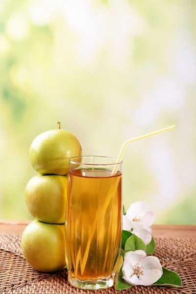 Glas äppeljuice och äpplen på träbord, på natur bakgrund — Stockfoto