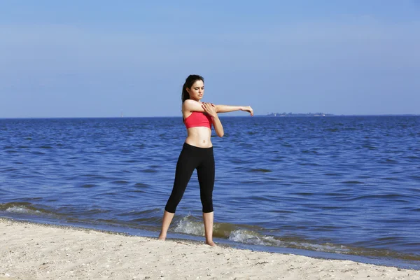 Jonge sportieve vrouw doen oefening op strand — Stockfoto