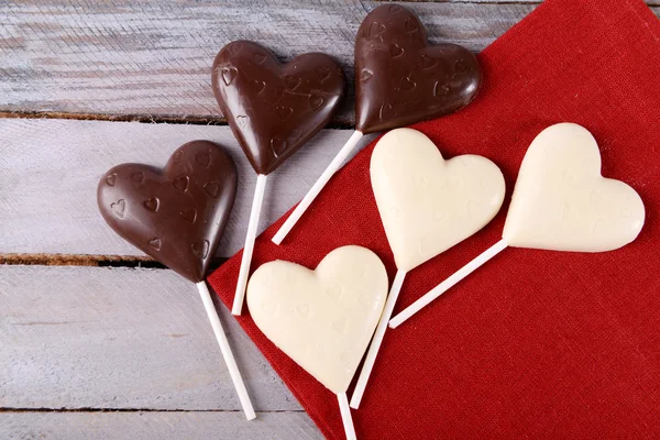 Chocolade hartvormige snoepjes op stokken op rode servet, close-up — Stockfoto