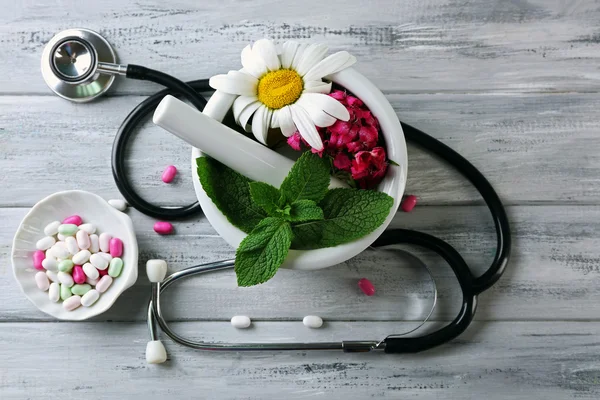 Medicina alternativa hierbas y estetoscopio sobre fondo de mesa de madera — Foto de Stock