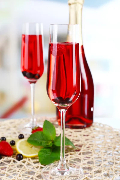 Pohár pezsgő, bogyók, homályos világos háttéren — Stock Fotó